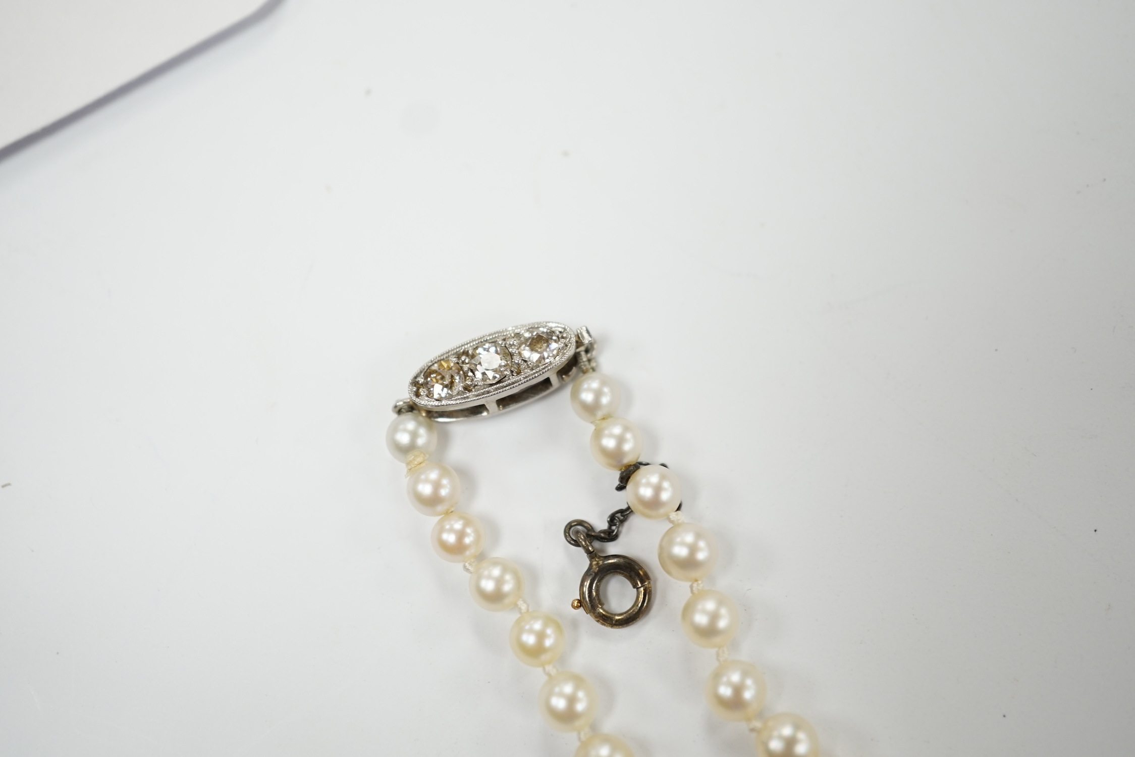 A single strand graduated cultured pearl necklace, with three stone diamond set white metal clasp, 44cm, Fair condition.